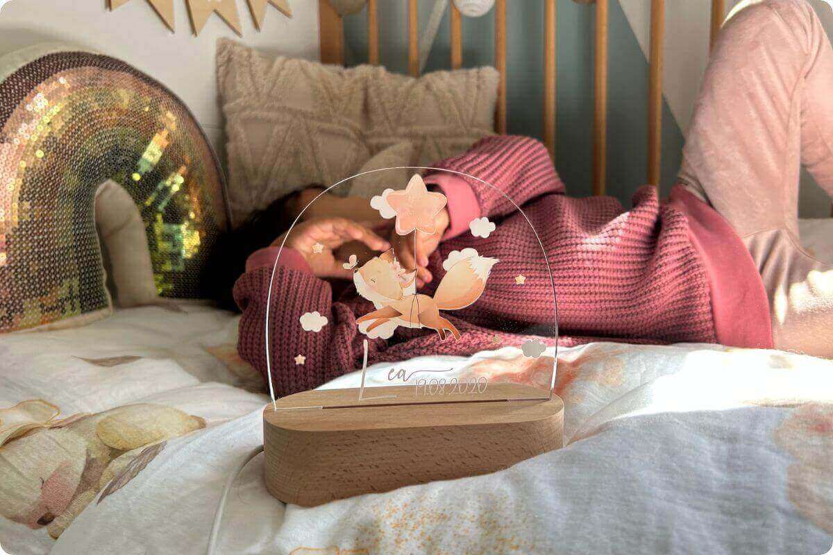 Alt-Tag: "Gemütliches Kinderzimmer mit personalisiertem Nachtlicht auf dem Nachttisch, das sanftes Licht verbreitet, während ein Kind friedlich im Bett schläft - warme, beruhigende Atmosphäre für süße Träume und erholsame Nächte