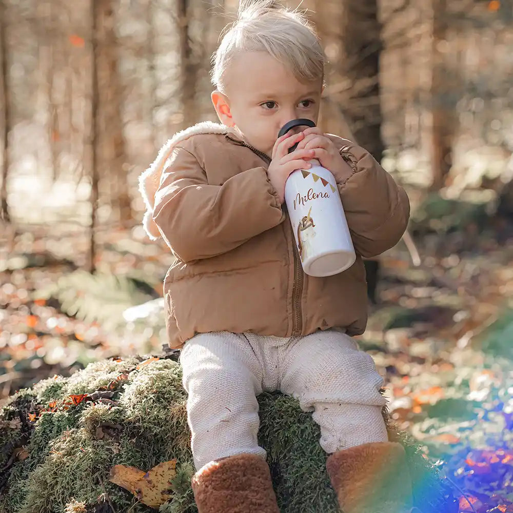 Enfant buvant à sa gourde personnalisée motif Licorne et guirlande en forêt — Kidsmood