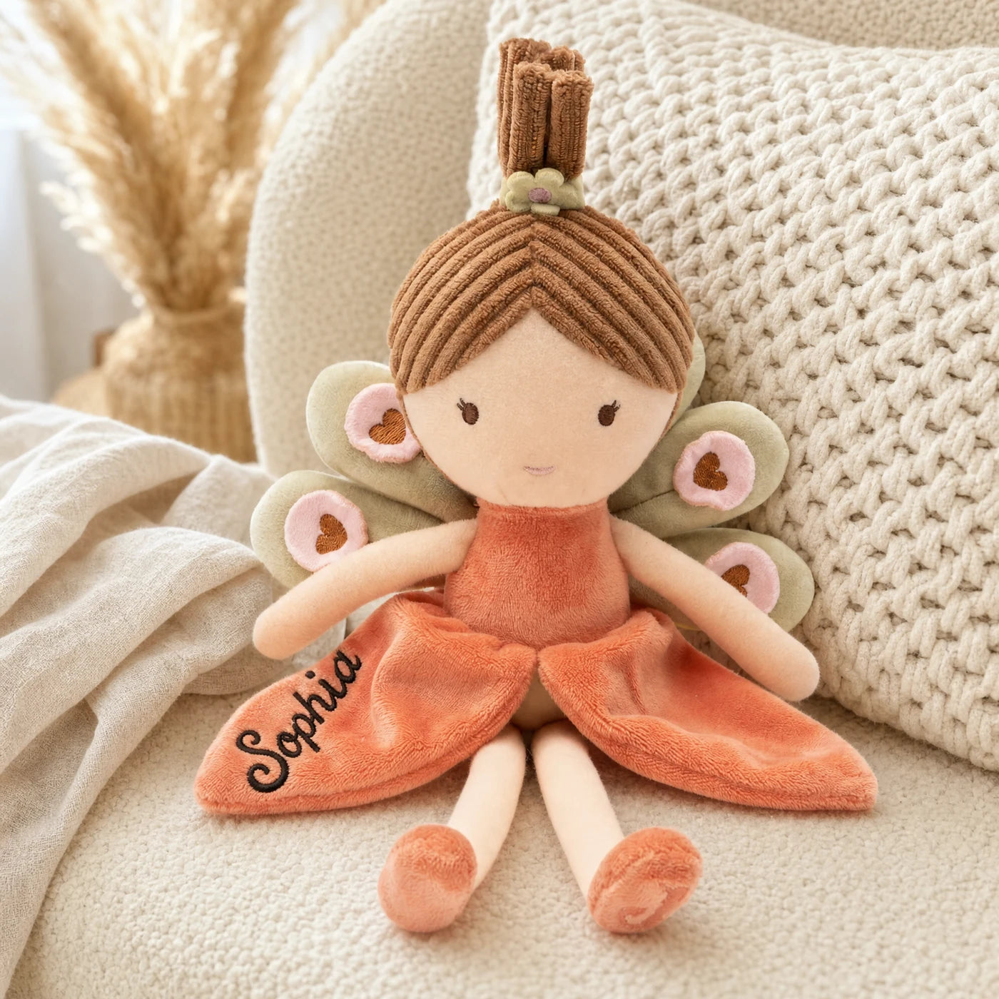 Peluche fée Jollein coloris Corail posée dans un fauteuil de chambre d'enfant — Kidsmood