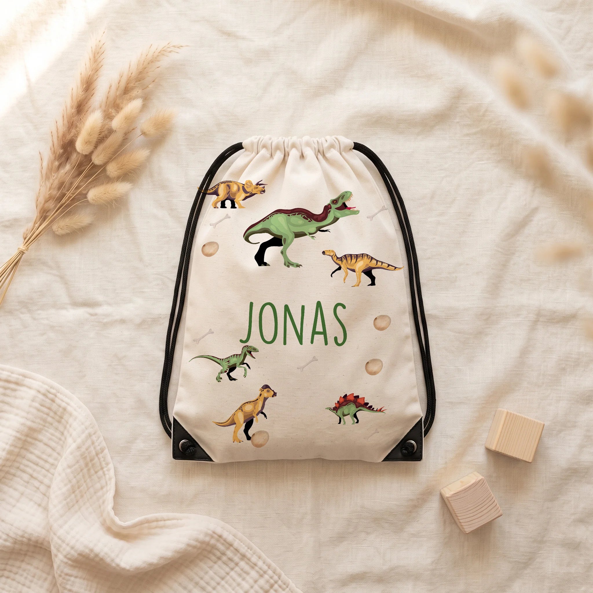 Sac de sport personnalisé posé à plat sur du lin, motif dinosaures — Kidsmood