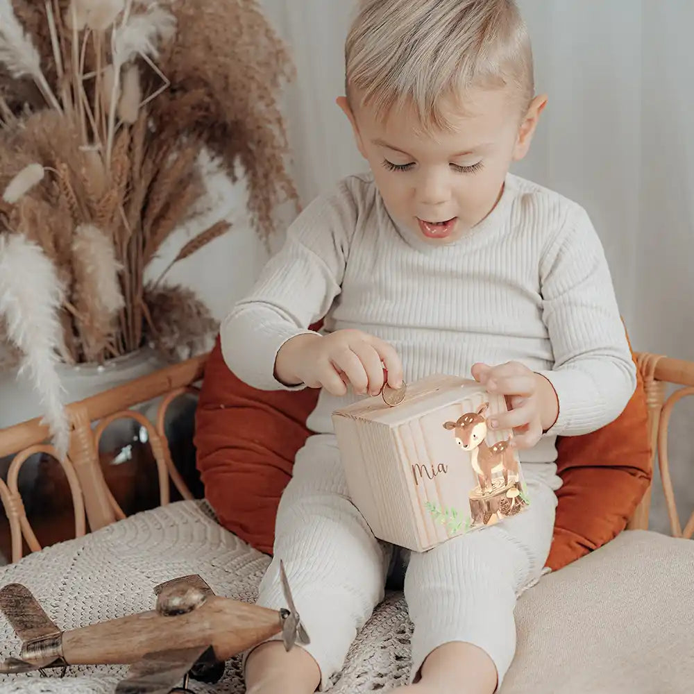 Enfant glissant une pièce dans sa tirelire personnalisée, motif biche et faon — Kidsmood