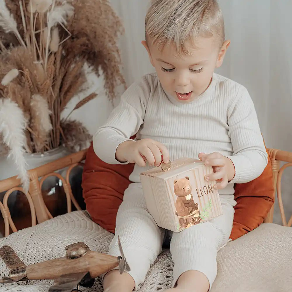 Enfant glissant une pièce dans sa tirelire personnalisée, motif ours des bois — Kidsmood