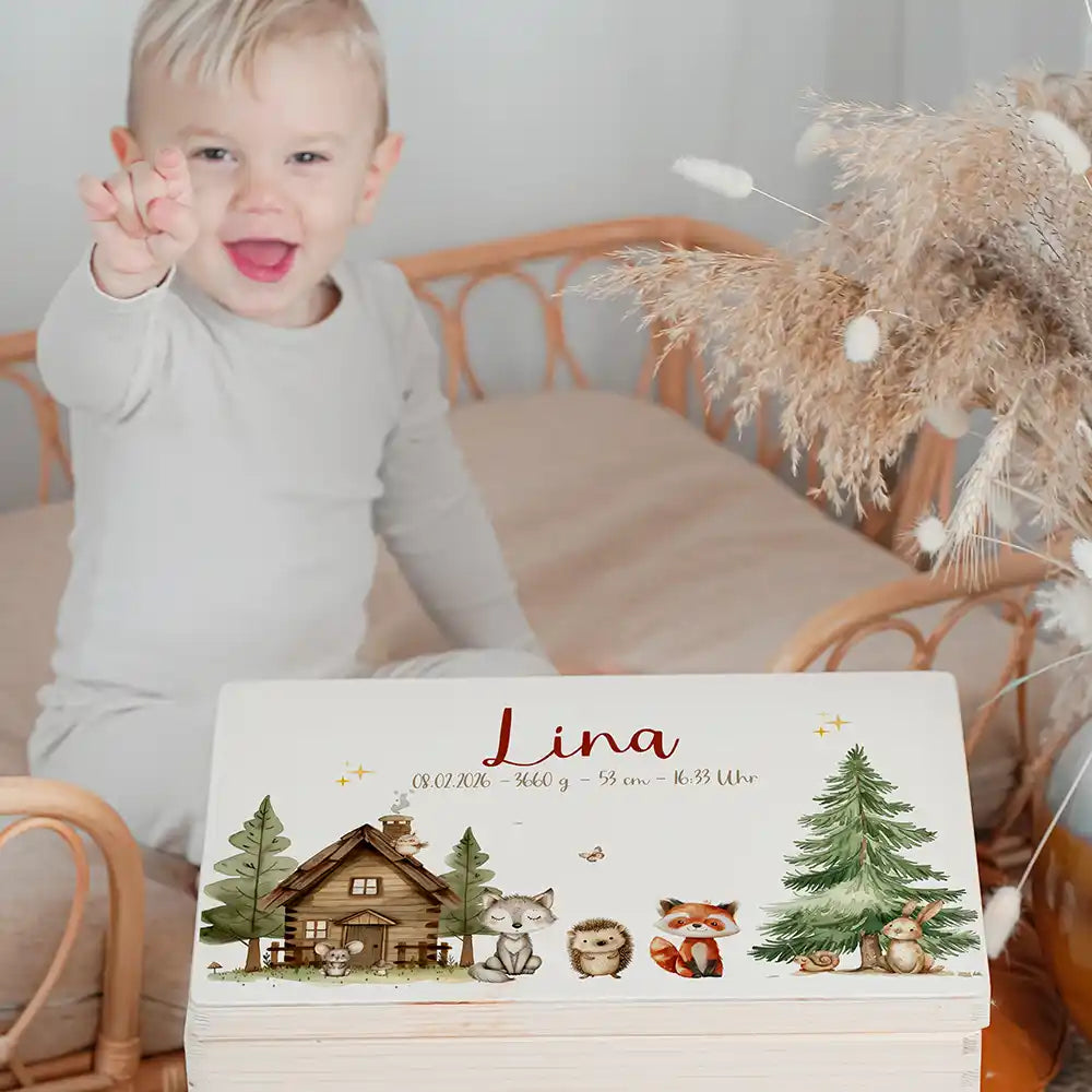 Boîte à souvenirs bébé personnalisée Cabane de la forêt – enfant souriant à côté du coffret personnalisé