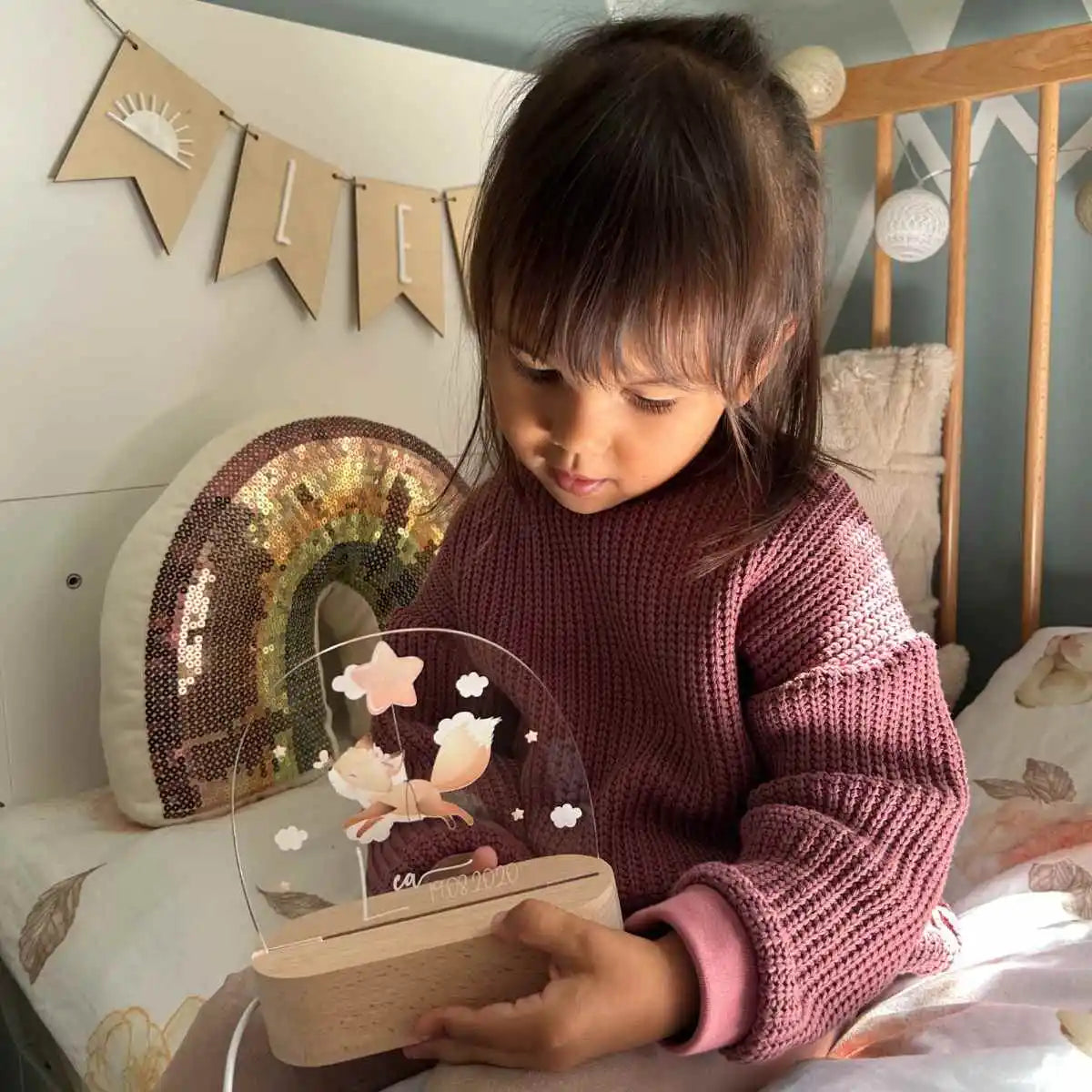 Lächelndes Mädchen schaltet ihr personalisiertes Fuchs-Nachtlicht ein - Kind mit leuchtendem Holznachtlicht in Herzform mit graviertem Namen im gemütlichen Kinderzimmer