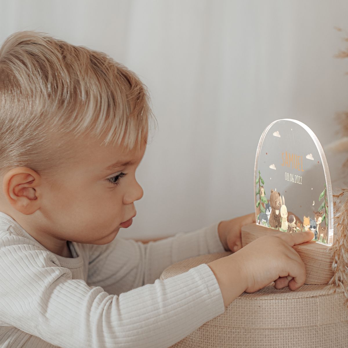 Junge im Schlafanzug hält stolz sein individuelles LED-Nachtlicht mit Waldtier-Motiv - personalisierte Schlafzimmerbeleuchtung sorgt für strahlende Kinderaugen zur Schlafenszeit